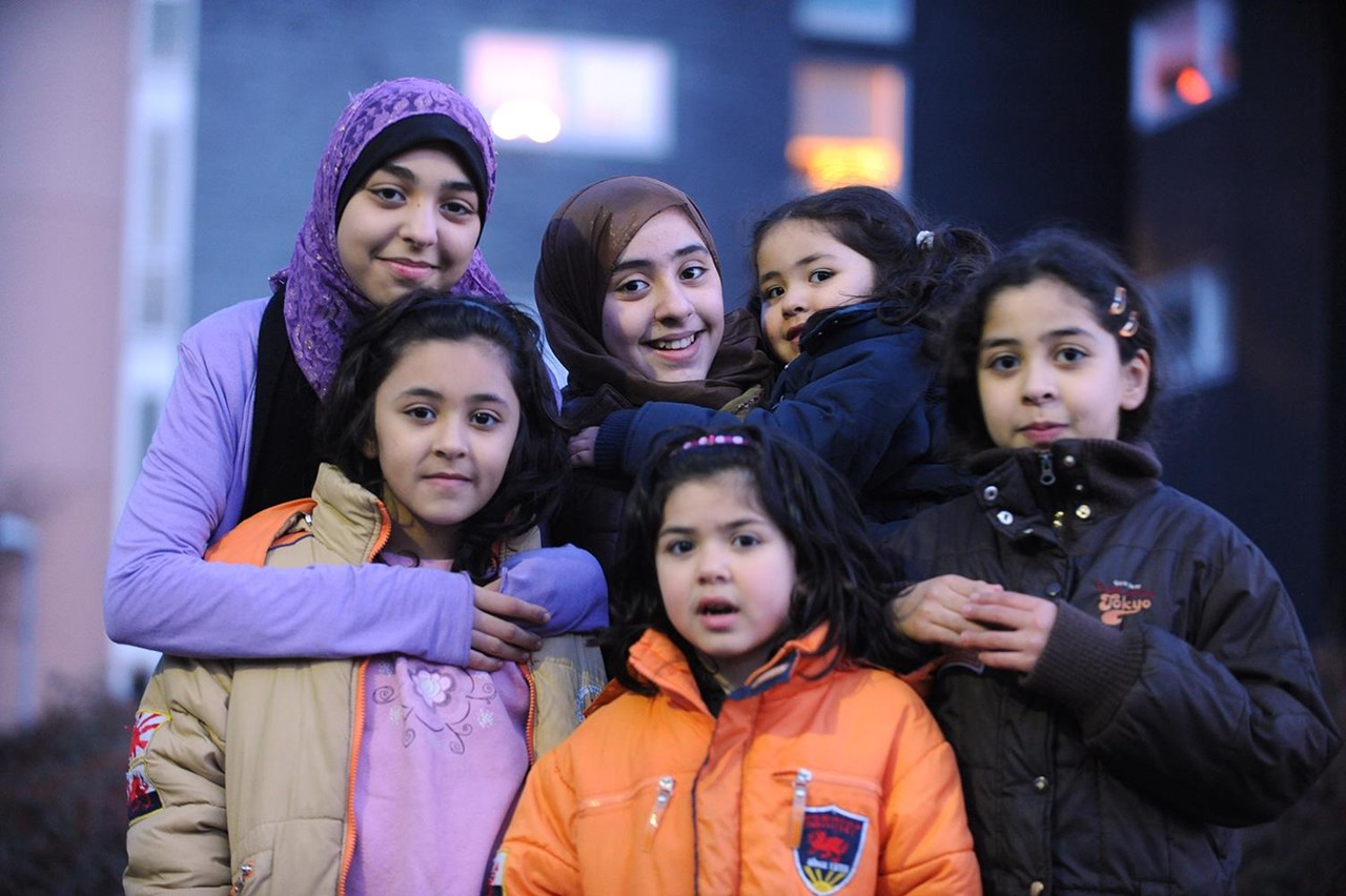 Sechs Kinder mit Migrationshintergrund unterschiedlichen Alters schauen in die Kamera