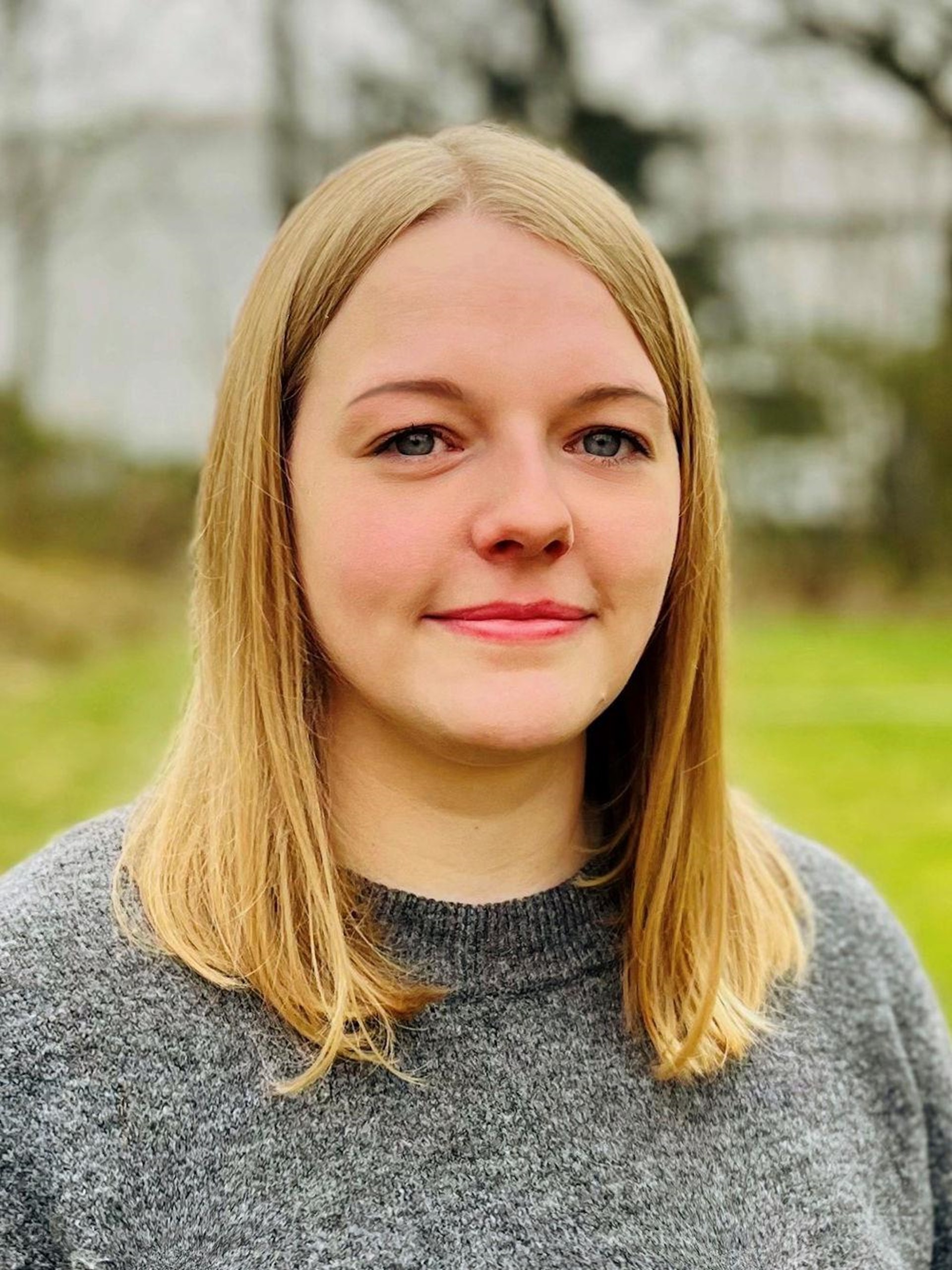 Porträtaufnahme einer jungen Frau mit  blonden, halblangen Haaren.