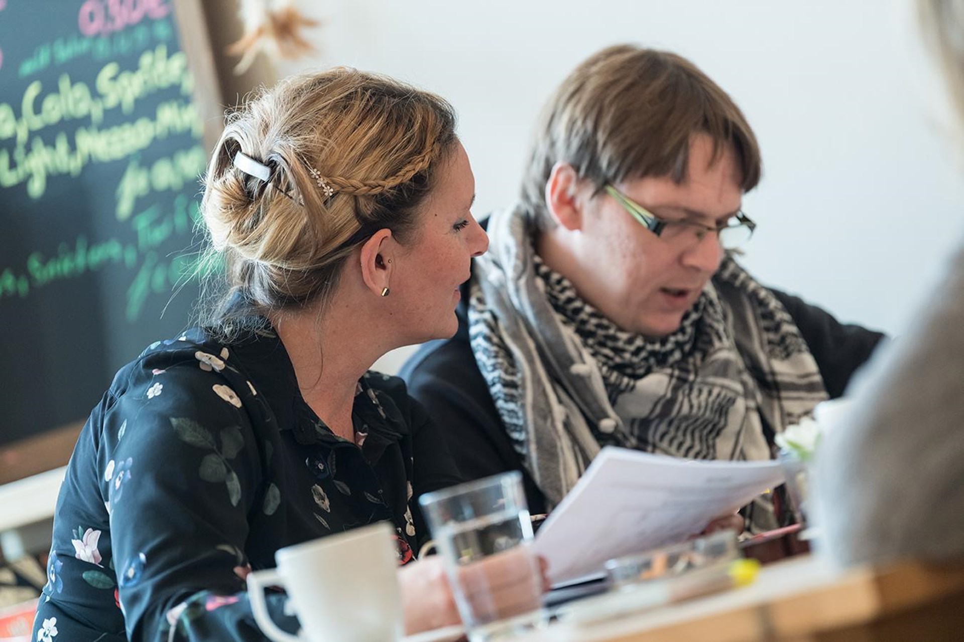 Caritas-Mitarbeiterin hilft einem Wohnungslosen beim Ausfüllen von Formularen