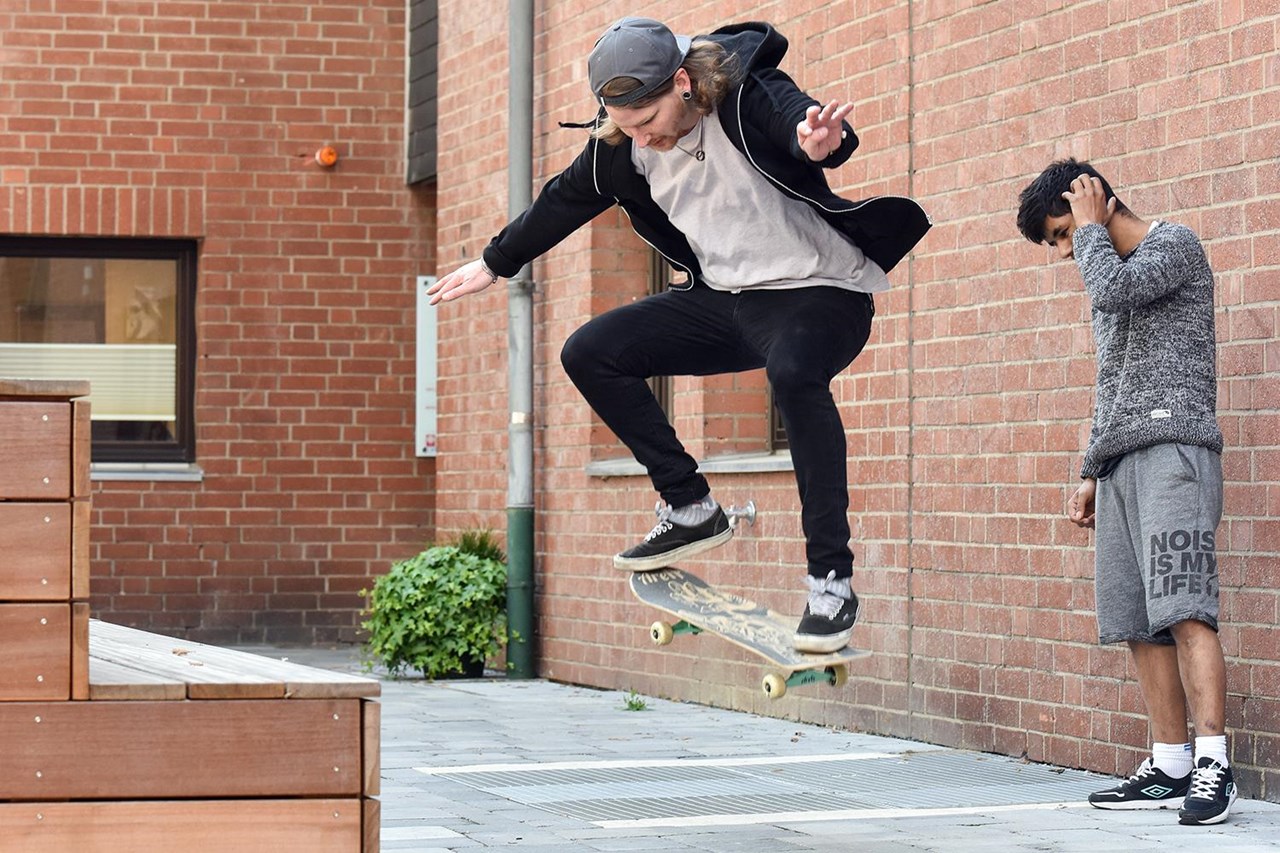 Zwei Jugendliche auf Platz mit Skateboard 